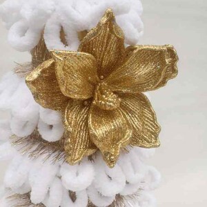 May include: A white and gold Christmas tree decoration with a large gold glitter flower on top.
