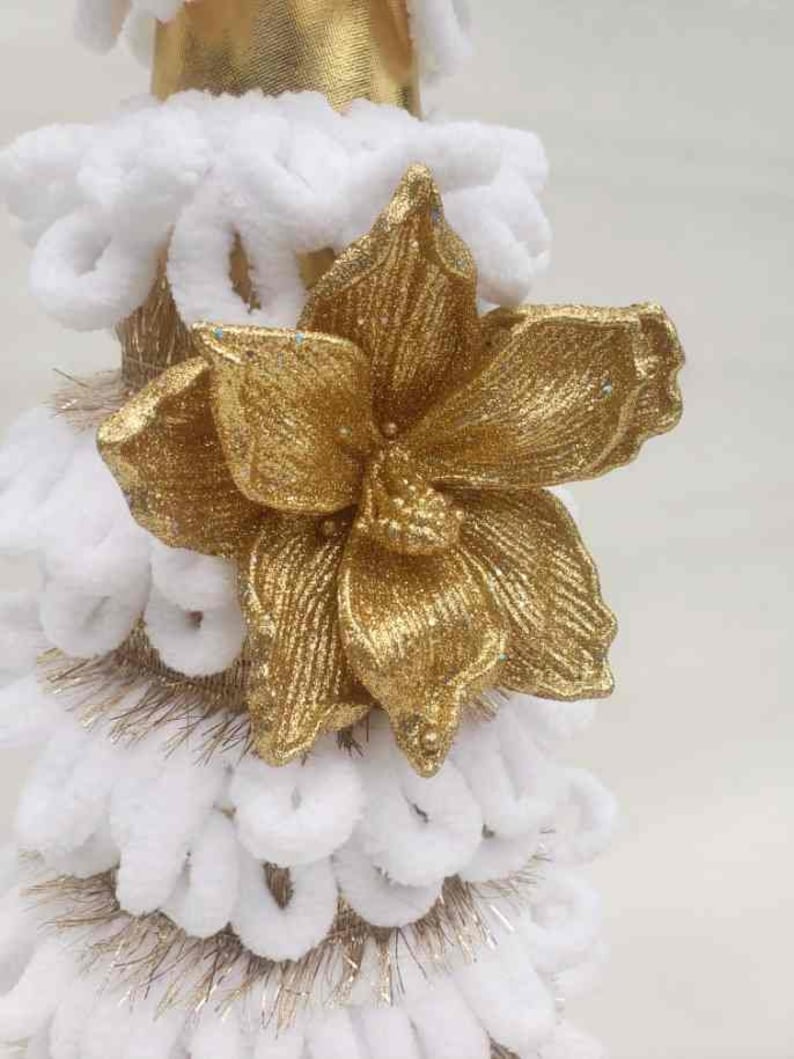 May include: A white and gold Christmas tree decoration with a large gold glitter flower on top.