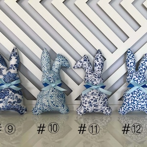 Peut inclure: Quatre lapins en peluche bleu et blanc &agrave; motifs avec des n&oelig;uds bleus. Les lapins sont num&eacute;rot&eacute;s de 9 &agrave; 12.