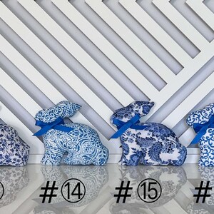 Peut inclure: Quatre figurines de lapin en tissu bleu et blanc avec des n&oelig;uds en ruban bleu. Les lapins sont num&eacute;rot&eacute;s 13, 14, 15 et 16.