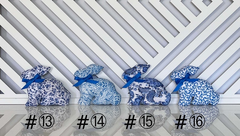Peut inclure: Quatre figurines de lapin en tissu bleu et blanc avec des n&oelig;uds en ruban bleu. Les lapins sont num&eacute;rot&eacute;s 13, 14, 15 et 16.