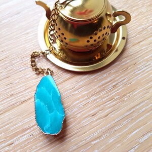 Peut inclure: Infuseur &agrave; th&eacute; en or avec un charme en agate bleu sarcelle attach&eacute; &agrave; une cha&icirc;ne.