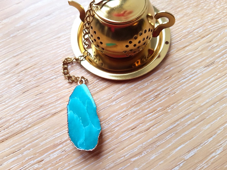Peut inclure: Infuseur &agrave; th&eacute; en or avec un charme en agate bleu sarcelle attach&eacute; &agrave; une cha&icirc;ne.