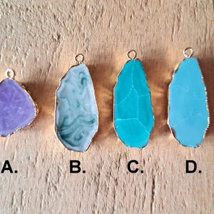 Peut inclure: Quatre pendentifs diff&eacute;rents, chacun pr&eacute;sentant une tranche d'agate unique avec une b&eacute;li&egrave;re en m&eacute;tal dor&eacute;. Les pendentifs sont &eacute;tiquet&eacute;s A, B, C et D. Le pendentif A est une agate violette claire, le pendentif B est une agate bleu clair et blanc, le pendentif C est une agate turquoise et le pendentif D est une agate bleu clair.