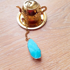 Peut inclure: Une infuseur &agrave; th&eacute; en forme de th&eacute;i&egrave;re dor&eacute;e avec une pierre pr&eacute;cieuse bleue attach&eacute;e &agrave; la cha&icirc;ne.