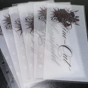 May include: A set of six clear plastic sleeves with holes for a binder. The sleeves are designed to hold and protect paper or cardstock. The top sleeve has a floral design and the text "Time-Out" written in cursive.