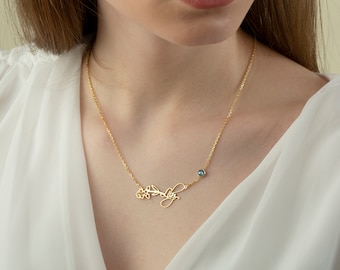 May include: A gold necklace with a delicate floral design and the name "Lily" written in cursive. A small blue gemstone is set on the chain.