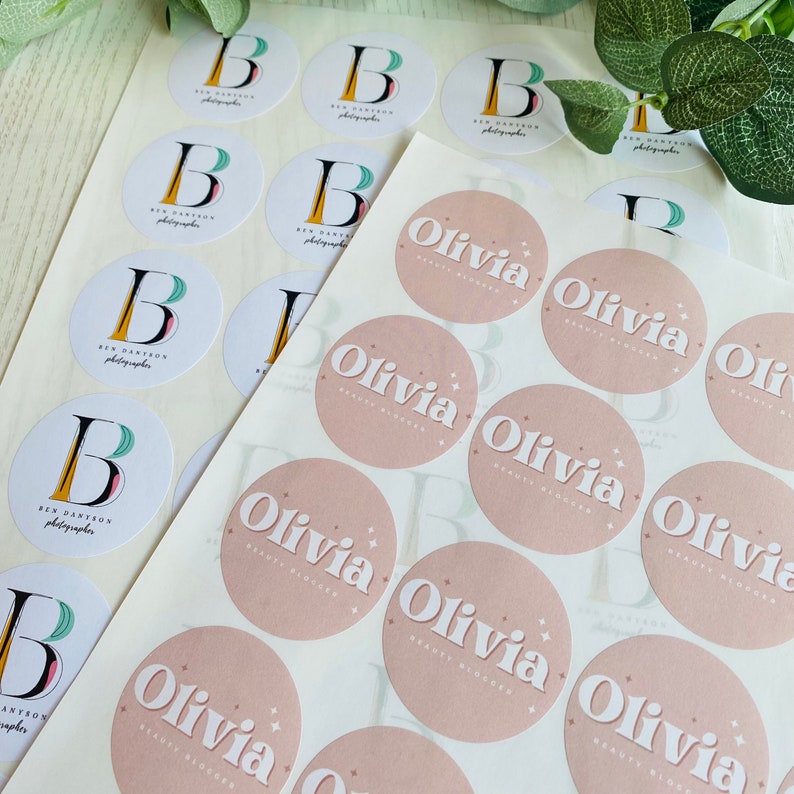 May include: A sheet of pink and white round stickers with the text "Olivia Beauty Blogger" printed on each sticker. The stickers are arranged in rows on a white background.