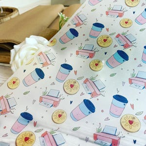 May include: White wrapping paper with a repeating pattern of pink and blue coffee cups, pink printers, and yellow heart-shaped cookies. Small green leaves and blue hearts are scattered throughout the design. The word "hello" is printed on the printer paper.