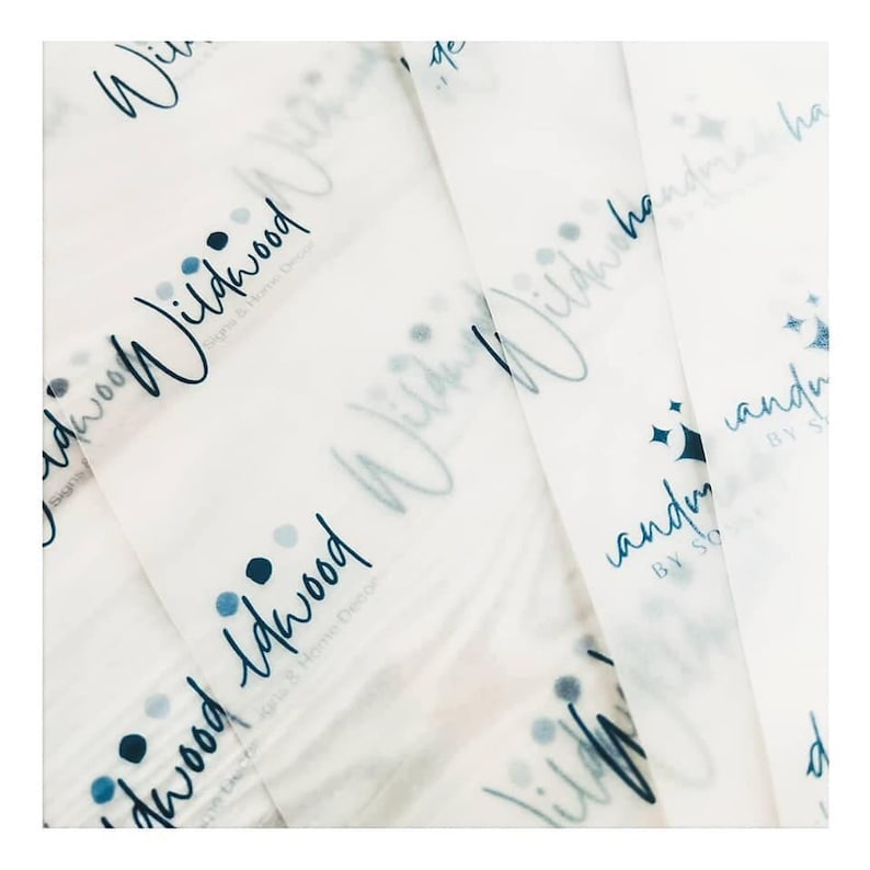 May include: White tissue paper with a repeating pattern of the word "Wildwood" in a handwritten font, along with the text "Signs & Home Decor". The design includes blue dots and stars.