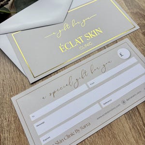 May include: A light grey gift voucher and envelope set. The voucher features gold foil text reading "a special gift for you" and "Eclat Skin Clinic". The envelope has gold foil text that reads "gift for you".
