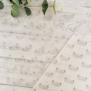 May include: Translucent white tissue paper with a repeating pattern of a decorative banner with the text "Sweet & Polished" in a script font. The banner is framed by floral elements in a light brown color.