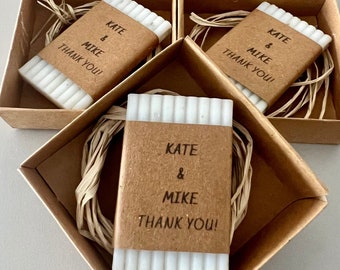 May include: Five small, white, rectangular bars of soap with brown paper labels. Each label reads "Kate & Mike Thank You!" The soaps are packaged in small, brown cardboard boxes with a straw-like material inside.