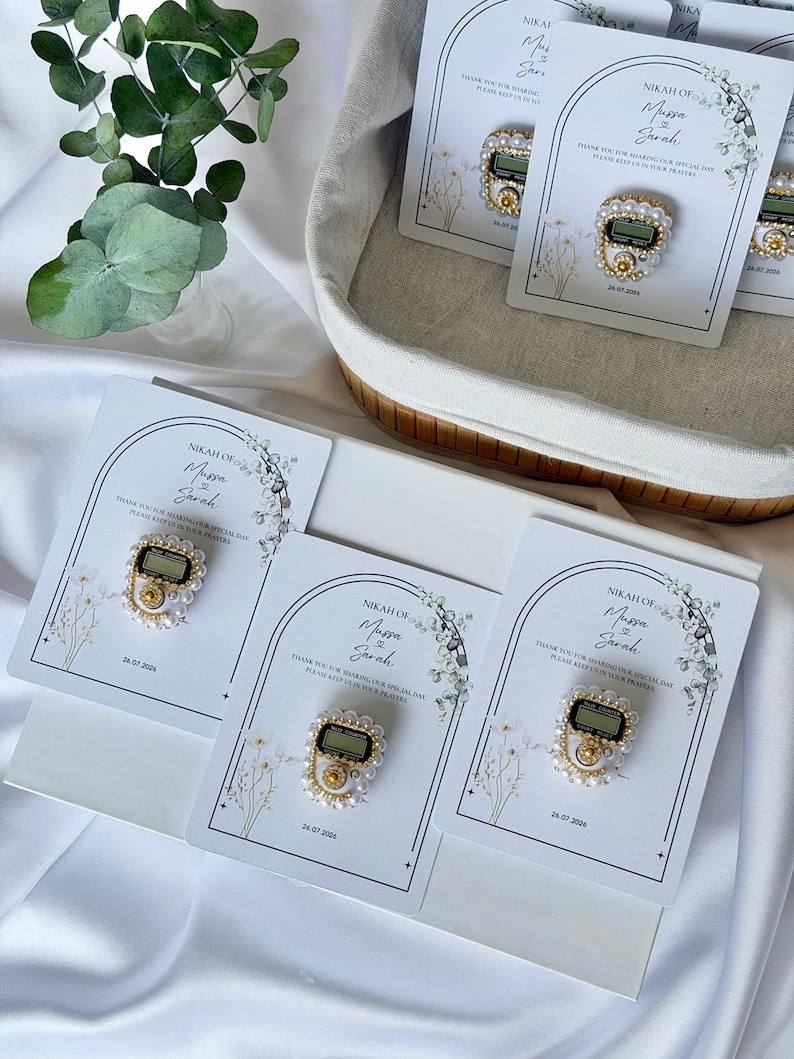 Personalized Islamic wedding favor featuring a digital tasbih counter attached to a custom Nikkah card with couple names and wedding date, elegant Muslim wedding guest gift display with floral design.
