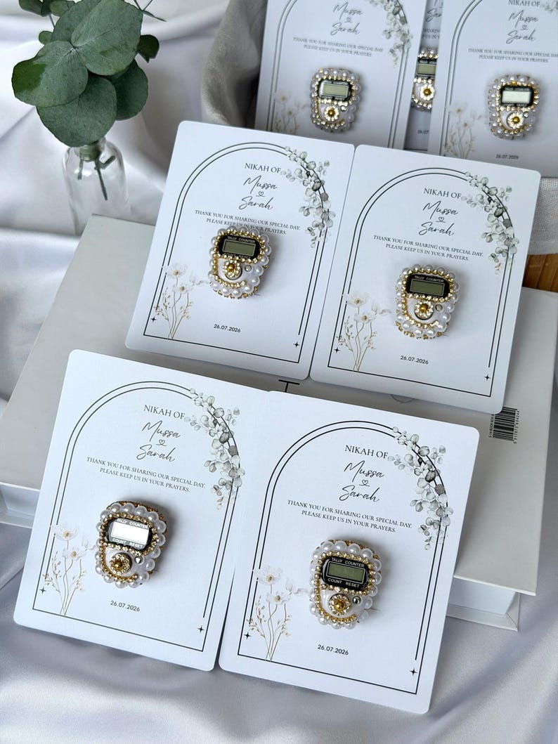 Personalized Islamic wedding favor featuring a digital tasbih counter attached to a custom Nikkah card with couple names and wedding date, elegant Muslim wedding guest gift display with floral design.