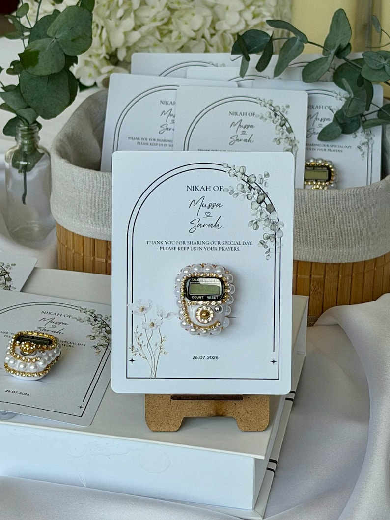 Personalized Islamic wedding favor featuring a digital tasbih counter attached to a custom Nikkah card with couple names and wedding date, elegant Muslim wedding guest gift display with floral design.