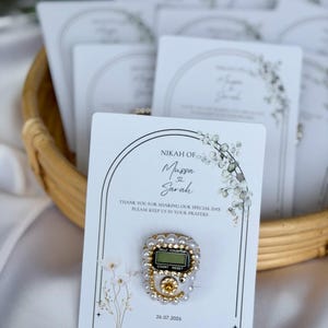Personalized Islamic wedding favor featuring a digital tasbih counter attached to a custom Nikkah card with couple names and wedding date, elegant Muslim wedding guest gift display with floral design.