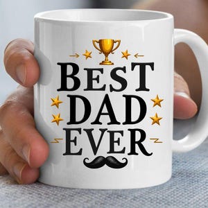 May include: White ceramic mug with the text "BEST DAD EVER" in black, decorated with gold stars, a trophy, and a mustache. The mug has a white handle and is held by a person.