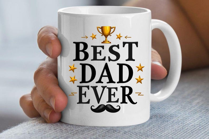 May include: White ceramic mug with the text "BEST DAD EVER" in black, decorated with gold stars, a trophy, and a mustache. The mug has a white handle and is held by a person.