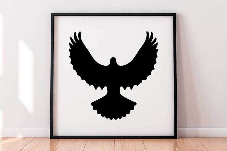 May include: A square black frame containing a white print with a solid black silhouette of a bird in flight with its wings spread wide. The bird is centered in the frame, displaying a detailed feathered wing shape and a fanned tail design.