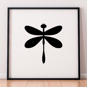 May include: A framed print featuring a minimalist black dragonfly silhouette against a white background. The dragonfly has four oval wings and a long, slender body. The artwork is displayed in a black frame, suitable for wall decor.