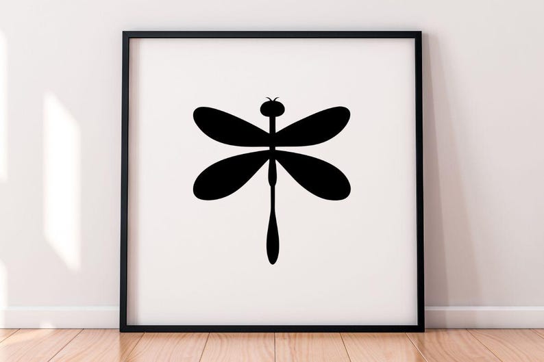 May include: A framed print featuring a minimalist black dragonfly silhouette against a white background. The dragonfly has four oval wings and a long, slender body. The artwork is displayed in a black frame, suitable for wall decor.
