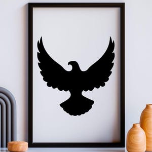May include: A black and white framed wall art print featuring a solid black silhouette of an eagle with wings spread wide in flight. The rectangular frame is black and thin, surrounding a white background that displays the centered bird graphic.