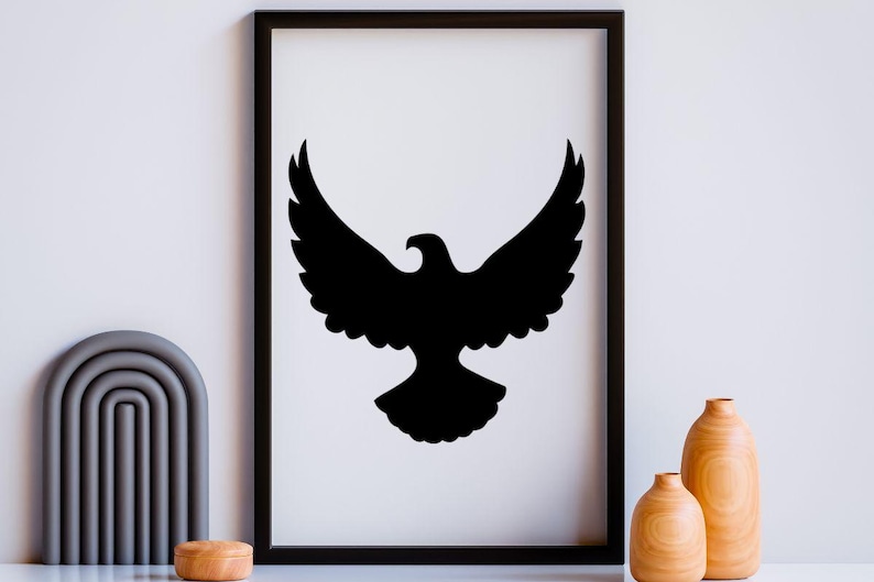 May include: A black and white framed wall art print featuring a solid black silhouette of an eagle with wings spread wide in flight. The rectangular frame is black and thin, surrounding a white background that displays the centered bird graphic.