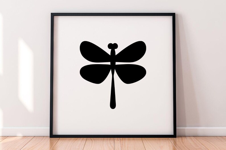 May include: A framed art print featuring a minimalist black dragonfly silhouette against a white background. The dragonfly has four rounded wings and a long, slender body. The artwork is displayed in a black frame.