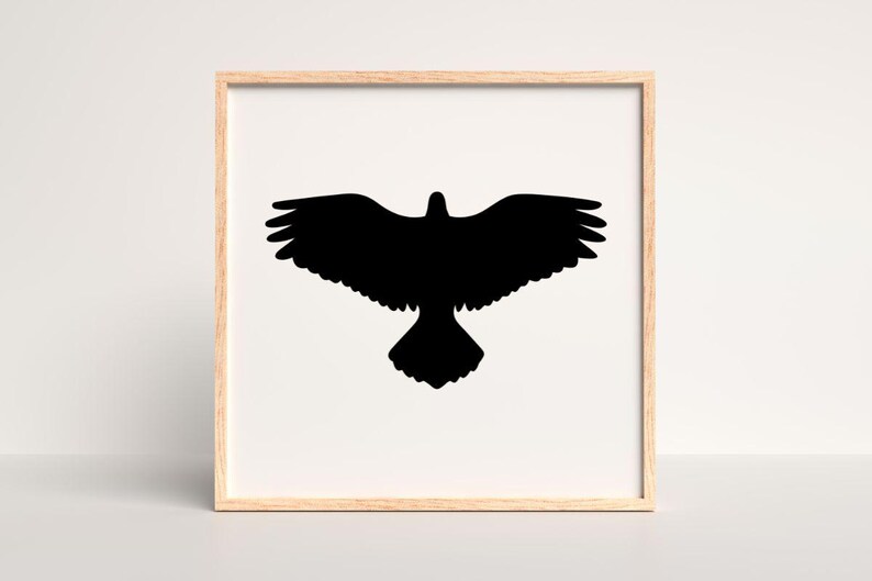 May include: A square wall art piece featuring a solid black silhouette of a bird with wings fully spread in flight, centered on a white background and enclosed within a light-toned wooden frame with a clean, simple border design.