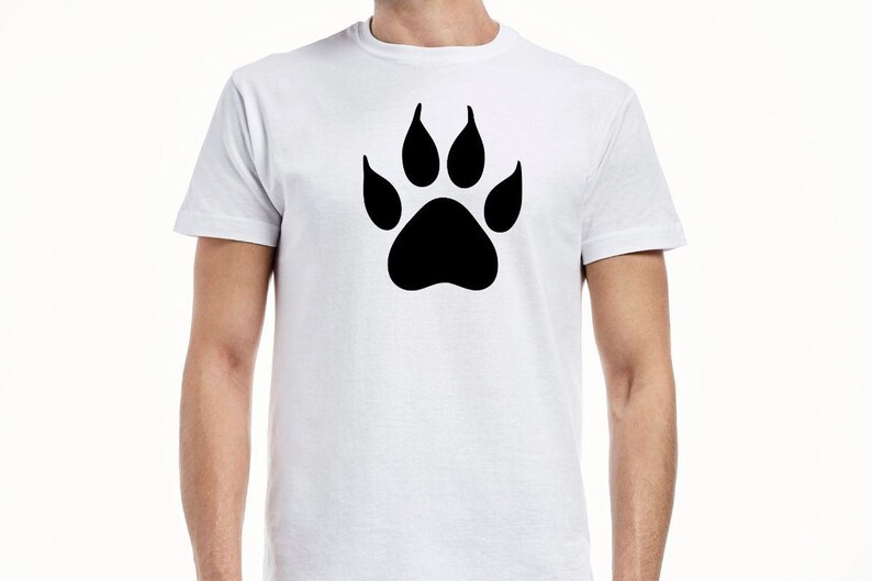 May include: A white short-sleeved t-shirt featuring a large, solid black animal paw print graphic centered on the chest. The garment has a classic crew neckline and a standard fit, showcasing a simple design with a bold, high-contrast black print.