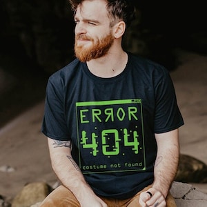 May include: A dark blue t-shirt with a green graphic of a computer error message that says "ERROR 404 costume not found".