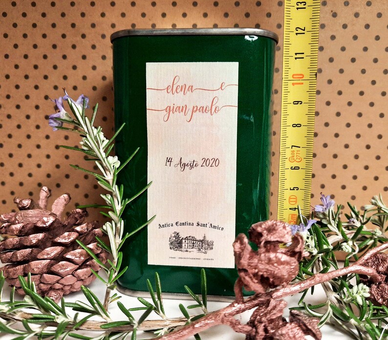 May include: A green metal can with a white label. The label has the text "elena e gian paolo" and "14 Agosto 2020". The label also has the text "Antica Cantina Sant'Amica".