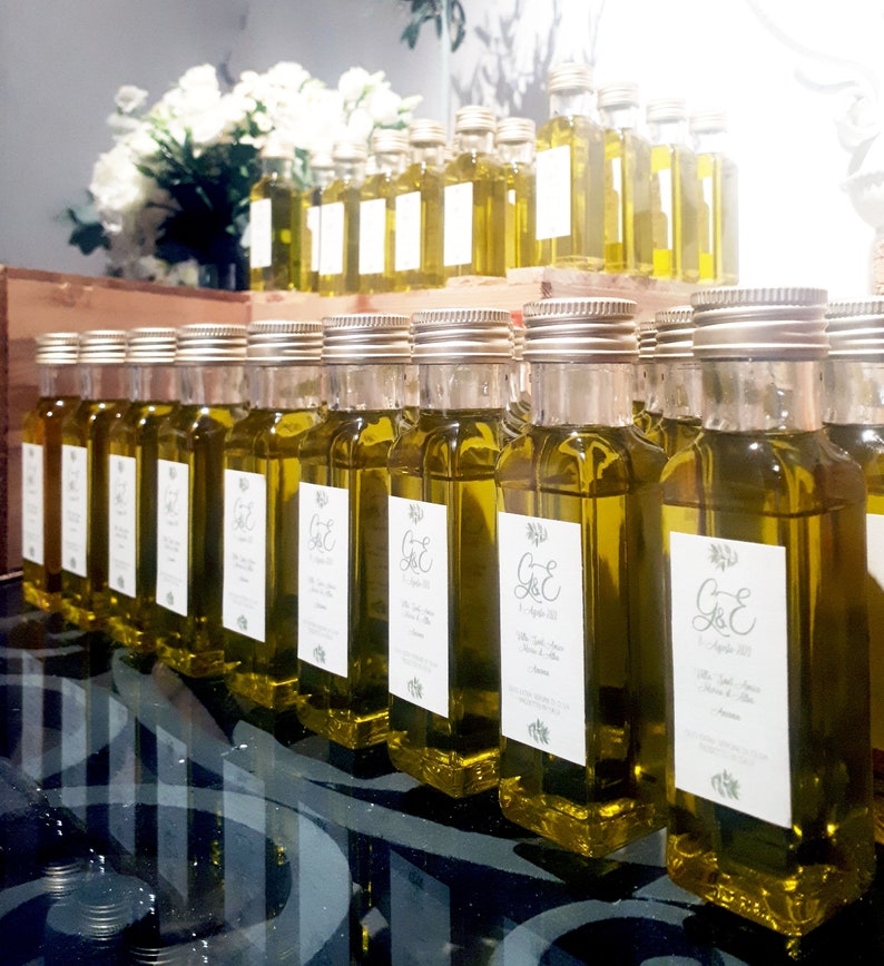 May include: A display of small glass bottles filled with olive oil, each with a personalized label featuring the initials "G&E" and the date "September 2023".