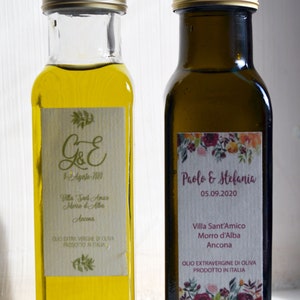 May include: Two glass bottles of olive oil with labels. The labels are personalized with the names "G&E" and "Paolo & Stefania" and the dates "8-Agosto-2020" and "05.09.2020". Both bottles have the text "Villa Sant'Amico Morro d'Alba Ancona" and "Olio Extra Vergine di Oliva Prodotto in Italia".