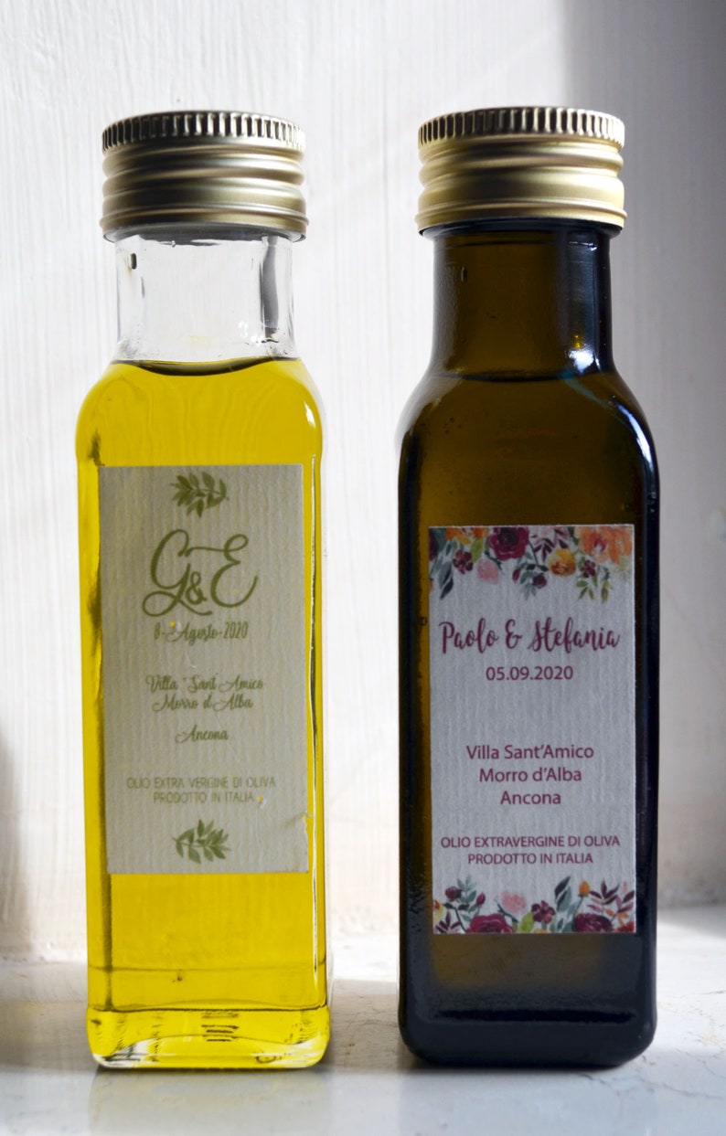 May include: Two glass bottles of olive oil with labels. The labels are personalized with the names "G&E" and "Paolo & Stefania" and the dates "8-Agosto-2020" and "05.09.2020". Both bottles have the text "Villa Sant'Amico Morro d'Alba Ancona" and "Olio Extra Vergine di Oliva Prodotto in Italia".