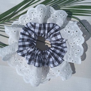 May include: A white lace hair scrunchie with a black and white checkered fabric center.