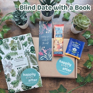 May include: A brown box with a white and green tropical leaf pattern. The box is labeled "Blind Date with a New Book" and "General Fiction". The box is surrounded by a bookmark, a chocolate bar, a tea bag, and a sticker that says "Happily Ever After".