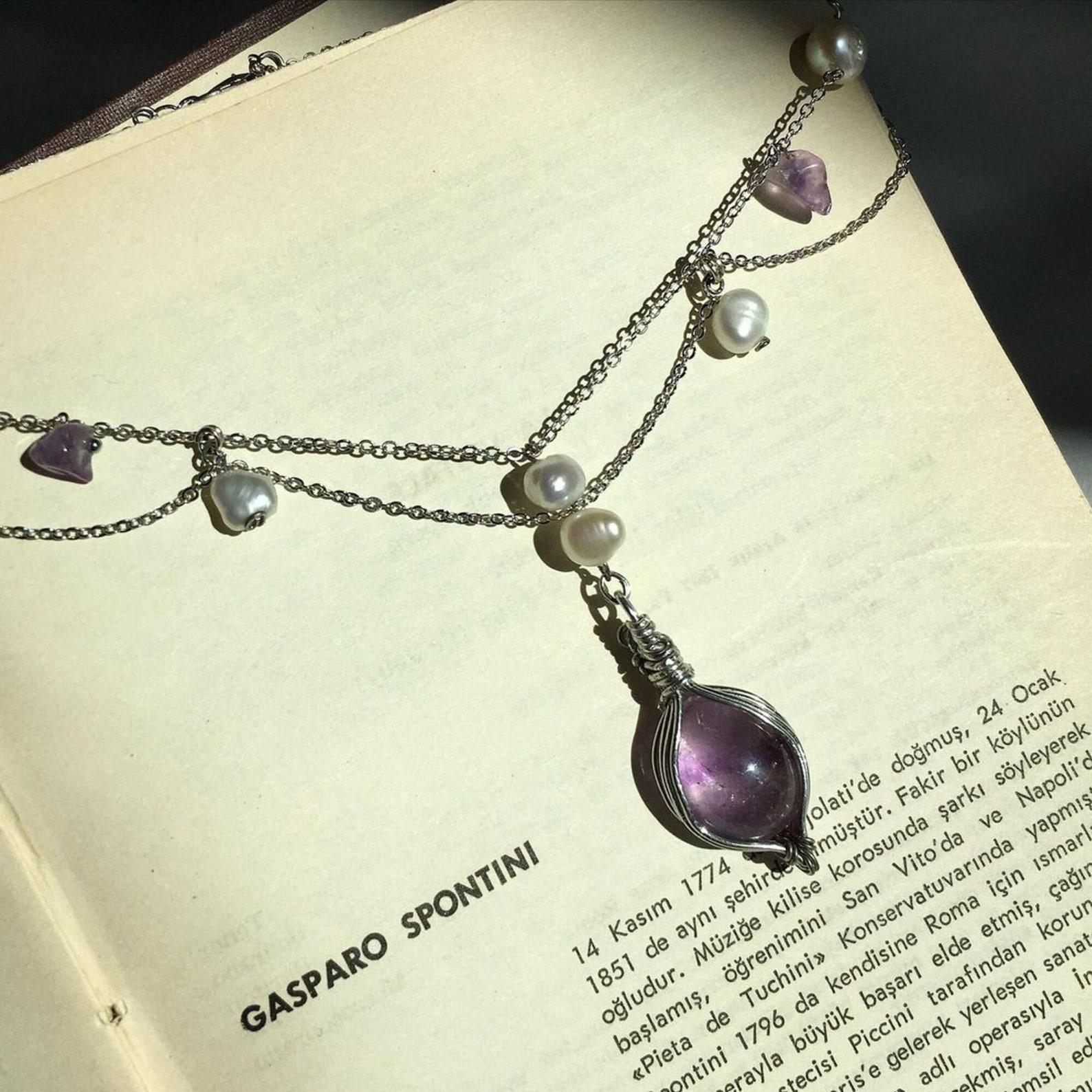 Victorian Amethyst and freshwater pearl choker with silver chains, displayed on an open vintage book.