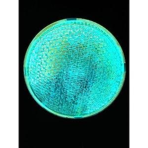 May include: A round, illuminated object with a textured, cracked glass-like surface. The object is primarily turquoise and green, with a bright, glowing appearance against a black background. The overall shape is circular.