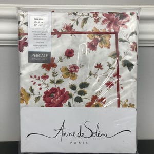 May include: A white euro sham with a floral pattern in shades of red, yellow, and green. The sham is packaged in plastic and has a label that reads "Anne de Solène Paris" and "Percale 80 fils/cm² 200 TC".