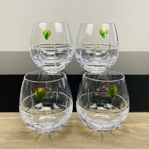 May include: Set of four clear glass tumblers with a geometric pattern. Each tumbler has a small green and gold label with a seahorse logo.