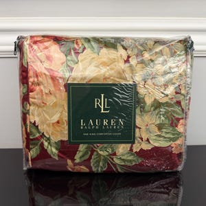 May include: A packaged Ralph Lauren king-size comforter cover. The cover features a floral pattern with large yellow and peach flowers, green leaves, and a burgundy background. The cover is sealed in clear plastic with a label that reads "RL LAUREN".