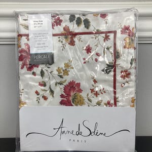 May include: A white king sham with a floral pattern in shades of red, yellow, and green. The sham is packaged in a clear plastic bag and has a label that reads "Anne de Solène Paris" and "Percale 80 fils/cm² 200 TC".