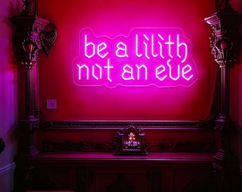 May include: A neon sign in bright pink against a red wall reads "be a lilith not an eve." The sign is mounted on a wall with ornate dark wood trim and decorative columns. A small, decorative clock sits on a wooden table below the sign.