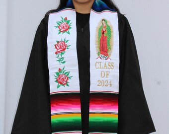 May include: A white graduation stole with a colorful serape pattern at the bottom. The stole features embroidered roses, a religious image, and the text "CLASS OF 2024".