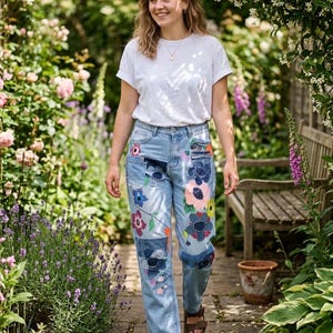 Peut inclure: Un t-shirt blanc uni à manches courtes associé à un jean en denim bleu clair délavé, orné de divers empiècements en tissu floral coloré et de motifs de fleurs brodés sur le devant des jambes, porté avec des sandales en cuir marron.