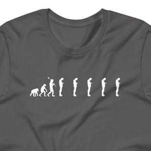 Peut inclure: Un t-shirt gris foncé avec un graphique blanc représentant l'évolution des humains, se terminant par une personne regardant un smartphone.