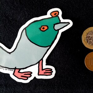 May include: A sticker of a cartoon bird with a green head, orange eyes, and a gray body. The bird has a long, pointed beak and pink legs. The sticker is on a black background and has the text "By Natty Peterkin" at the bottom.