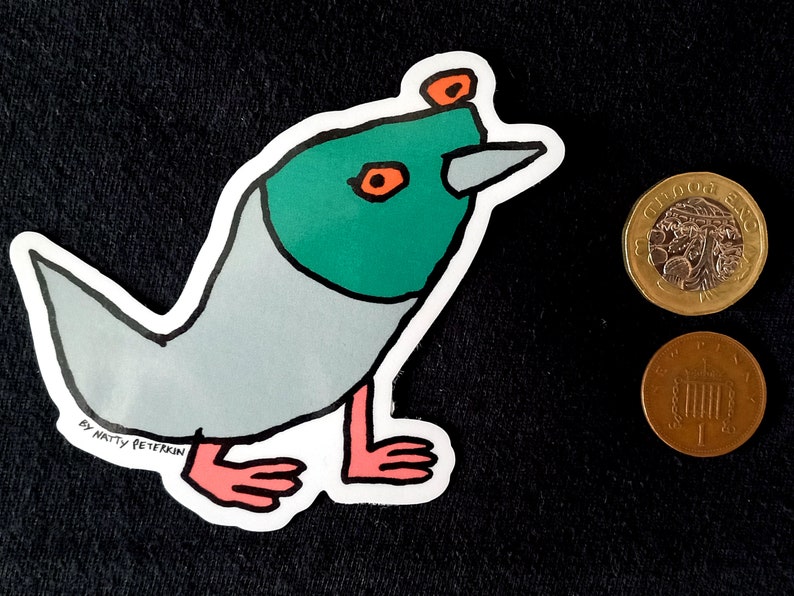 May include: A sticker of a cartoon bird with a green head, orange eyes, and a gray body. The bird has a long, pointed beak and pink legs. The sticker is on a black background and has the text "By Natty Peterkin" at the bottom.